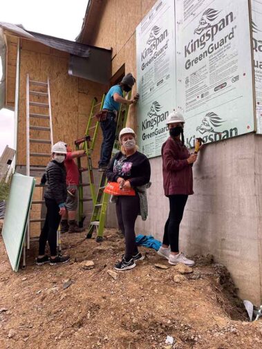 Photo of Hanna Resource Group team members volunteering at a Habitat for Humanity home building project -- applying plywood to side of a home.